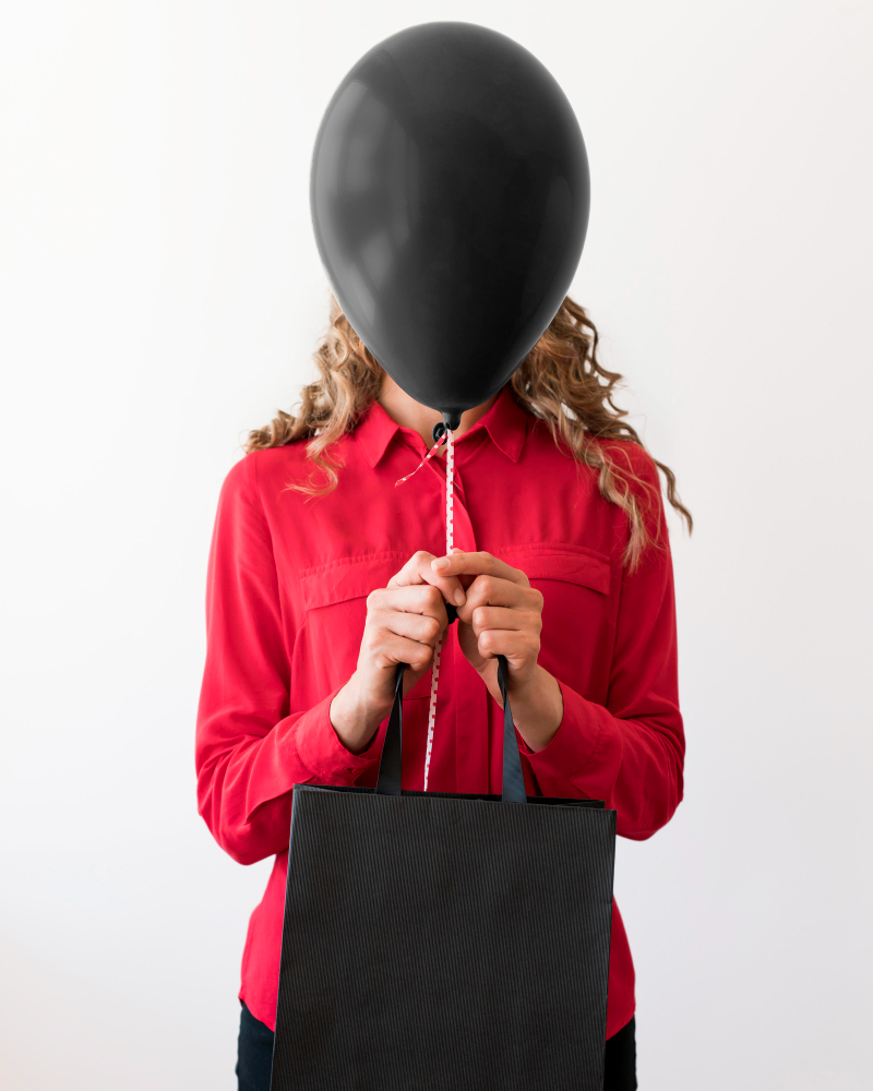 woman holding bag black balloon covering her face